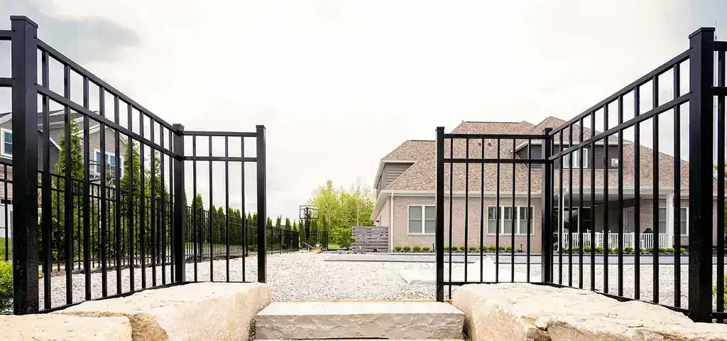 An open ornamental iron double gate between cut-stone piers